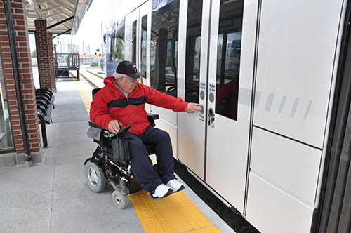 man in wheelchair boarding a trax vehicle